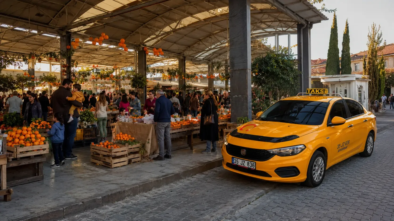 Kapalı Pazar Yeri'nde şenlik: mandalina kasaları, süslü stantlar ve kalabalık; kenarda bekleyen taksi